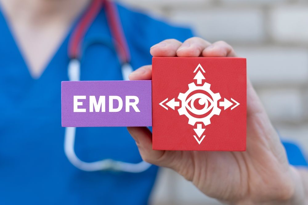 A healthcare professional holds two blocks reading "EMDR" alongside an eye movement symbol, clearly illustrating what EMDR in Palm Beach County, FL is and how it works as an evidence-based approach to trauma reprocessing. For anyone whose story resembles the characters in The Pitt, EMDR therapy in Palm Beach County, FL offers a proven path toward lasting relief from PTSD and unresolved traumatic memories. An EMDR therapist in Palm Beach County, FL can help you understand whether this approach is right for you.