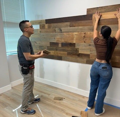 Two members of the Mangrove Therapy Group team work together to install reclaimed wood paneling on a therapy office wall, carefully placing each board to create a warm, rustic accent wall. This hands-on build-out reflects the level of care and intention that defines this Delray Beach therapy practice — every design choice was made with the client's comfort in mind. Creating a space that feels genuinely welcoming is part of what sets Mangrove apart as a trusted therapist in Delray Beach, FL.