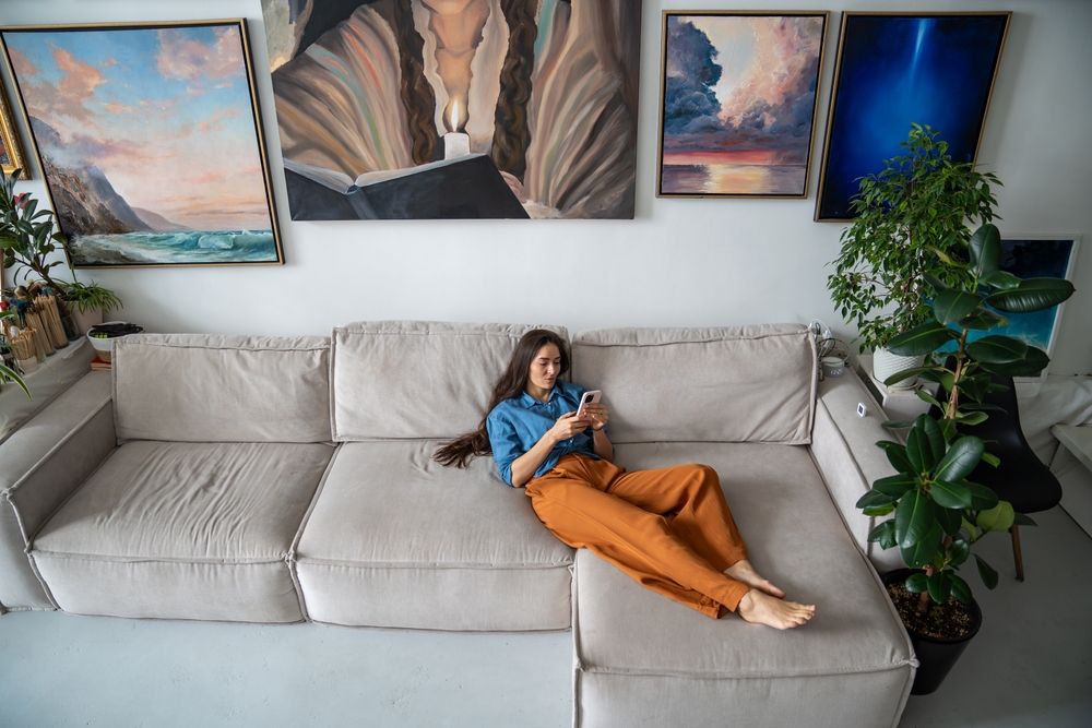 A young woman in a denim shirt and rust-colored pants lounges on a large beige couch, casually using her smartphone. This represents how one may avoid responsibilities. Learn more about how EMDR therapy in Palm Beach, FL can offer support by searching for EMDR group therapy in Palm Beach County, FL. An EMDR therapist in Miami, FL can provide support today. 33431 | 33432 | 33486