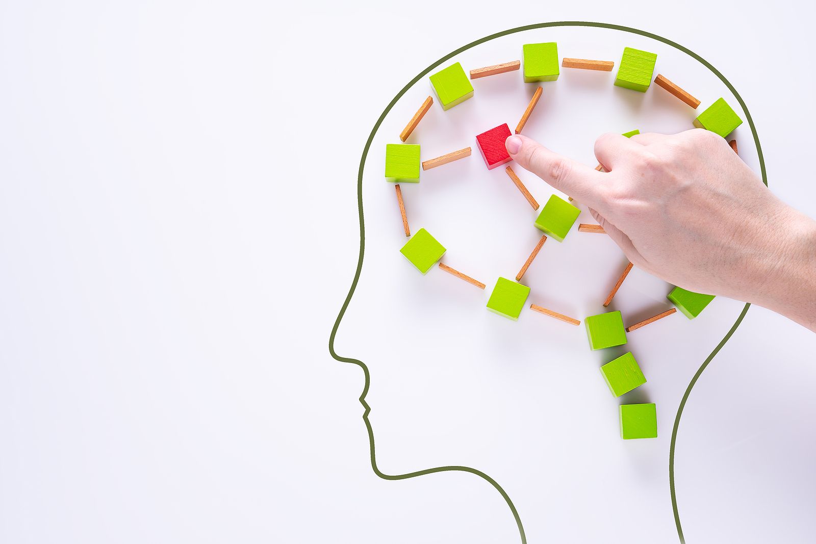 Conceptual image representing brain processes and memory. A hand is placing a red wooden block among green blocks connected by wooden sticks, all arranged inside the outline of a human head. The image symbolizes neural connections and cognitive reprocessing with the help of an EMDR therapist in Palm Beach County, FL. Learn more about EMDR in Palm Beach County, FL can offer support. Search for EMDR in Palm Beach County, FL for support today. 33435 | 33426 | 33487
