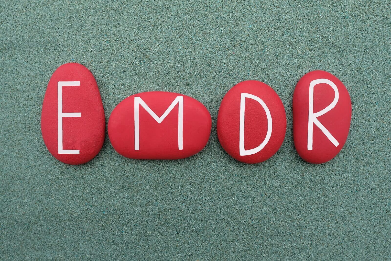 Four red stones arranged to spell “EMDR” against a textured background. This visual represents EMDR therapy in Palm Beach County, FL, a trauma treatment method offered by EMDR therapists in Miami, FL and Boca Raton, FL for emotional healing.