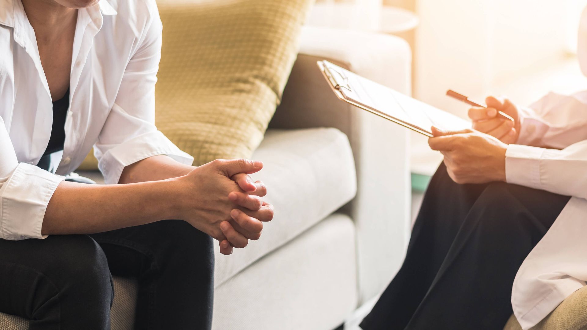 A close-up view of a therapy session where a person sits across from a counselor holding a clipboard, illustrating the compassionate support of a trauma therapist near Boca Raton, FL. This setting is common for those undergoing trauma therapy in Delray Beach, FL or seeking trauma treatment in Palm Beach, FL.
