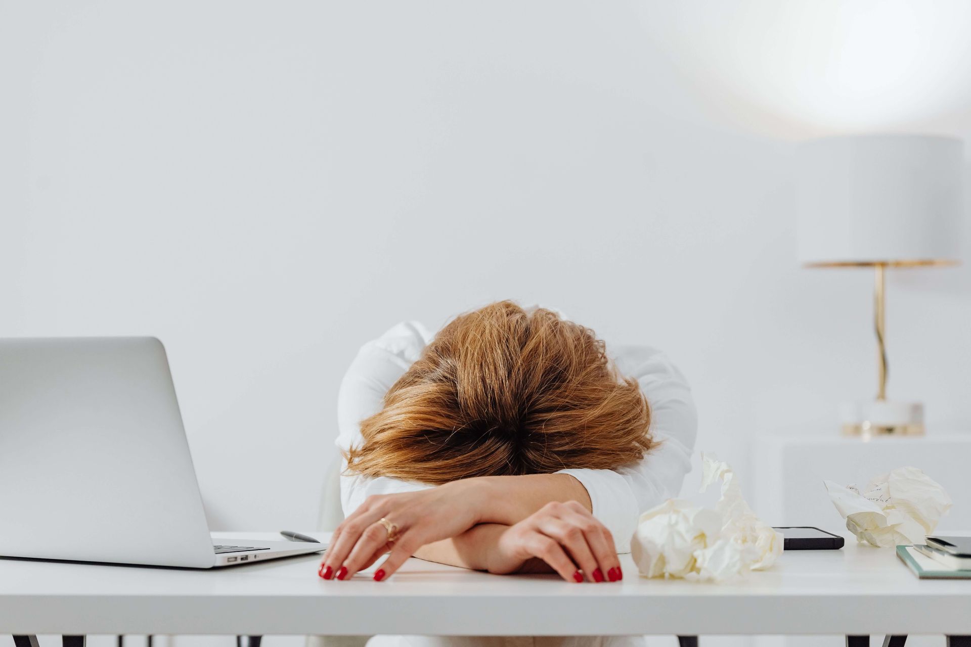 A professional woman rests her head on her desk in exhaustion, capturing the hidden internal struggle that high-functioning addiction can create beneath a polished exterior. This is exactly the kind of quiet suffering that addiction counseling in Delray Beach, FL is designed to address — before things have to fall apart visibly. An addiction therapist in Palm Beach County, FL can help you understand what's driving the pattern and build a more sustainable way forward.