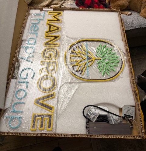 The custom Mangrove Therapy Group neon sign arrives in its packaging, featuring the practice name in colorful lettering alongside the iconic mangrove tree logo. This finishing touch was one of the final pieces installed in the new office of this well-known therapist in Delray Beach, FL, adding a vibrant and welcoming focal point to the space. It's a fitting symbol for a practice that has become a cornerstone of trauma therapy in Delray Beach, FL since opening its doors in 2022.