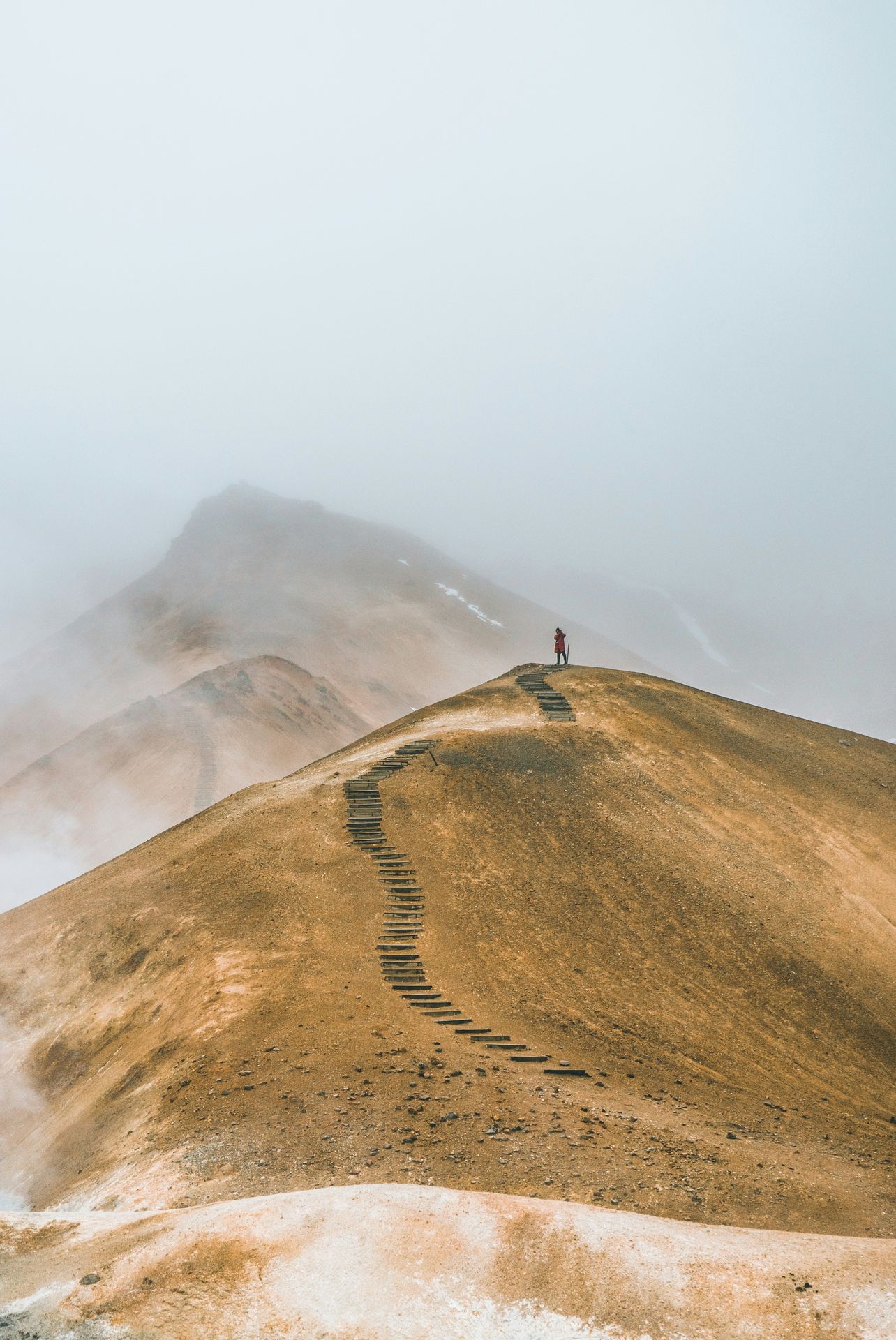 A lone traveler stands atop a winding mountain path enveloped in mist, symbolizing the emotional journey faced in trauma therapy in Delray Beach, FL. The image reflects the resilience supported by a trauma therapist in Delray Beach, FL and highlights the healing process offered by trauma treatment in Palm Beach County, FL.