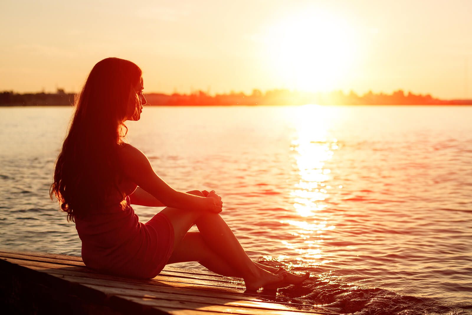 A woman sits on a dock at sunset, gazing peacefully over the water in quiet reflection. This sense of calm and groundedness is what many clients work toward through EMDR in Palm Beach County, FL. For those seeking an EMDR therapist in Palm Beach County, FL, this kind of emotional freedom is an achievable outcome of the healing process.