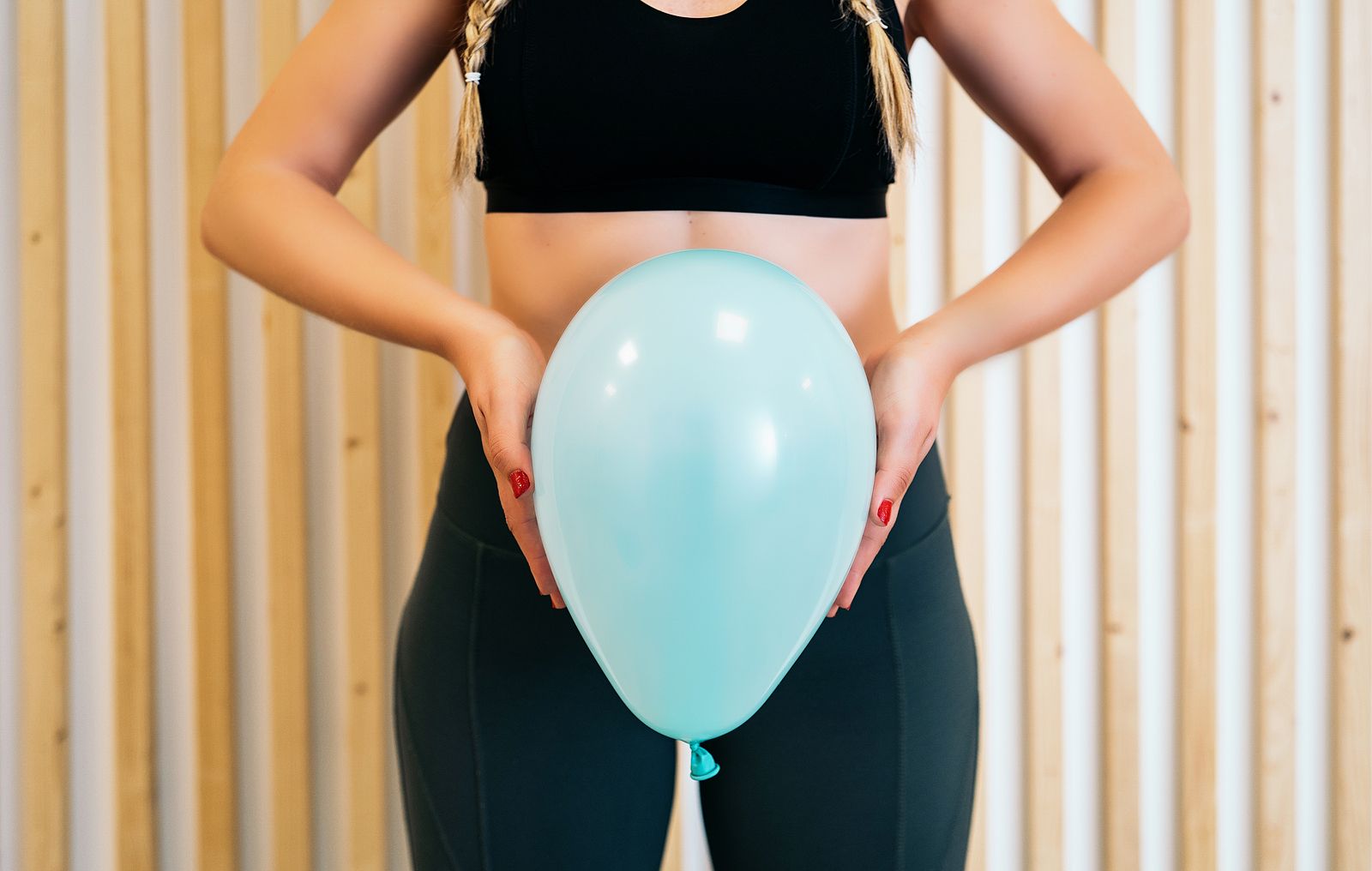 A woman in athletic wear holds a light blue balloon in front of her lower abdomen, symbolizing the connection between breath, pelvic floor function, and trauma recovery. Learn more about the benefits of trauma treatment in Palm Beach County, FL for addressing past trauma. Search for PTSD treatment in Palm Beach, FL and how a trauma therapist near Boca Raton, FL can help. 33444 | 33483 | 33445