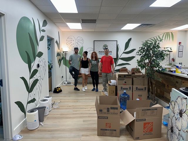 The Mangrove Therapy Group team walks through their nearly complete new office on move-in day, surrounded by moving boxes while the stunning tropical hallway mural and reclaimed wood reception desk are visible in the background. This candid moment captures the excitement and energy of a Delray Beach therapy practice stepping into a new chapter — a space built from scratch to support the healing of every client who walks through the door. For those seeking EMDR therapy in Delray Beach, FL.