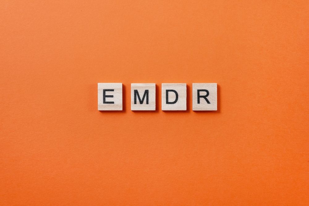 Wooden letter tiles spelling EMDR on an orange background, representing the EMDR therapy in Palm Beach County, FL and EMDR intensives in Palm Beach County, FL available for those ready to begin EMDR in Palm Beach County, FL.