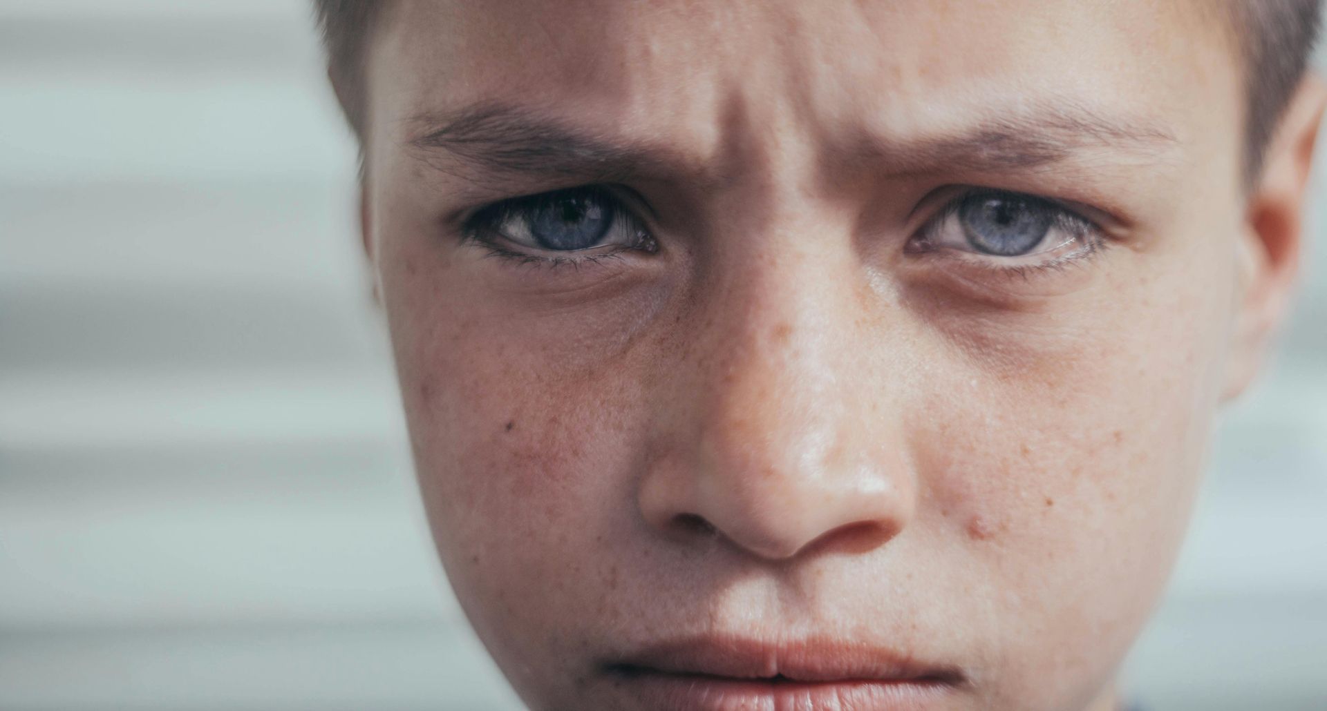 A close-up of a young boy with intense, furrowed brows and striking blue eyes, conveying emotional pain and distress. This powerful image represents the emotional struggles often treated through EMDR therapy in Palm Beach County, FL. It’s reflective of clients supported by EMDR group therapy in Palm Beach County, FL and individual care from an EMDR therapist in Palm Beach County, FL.