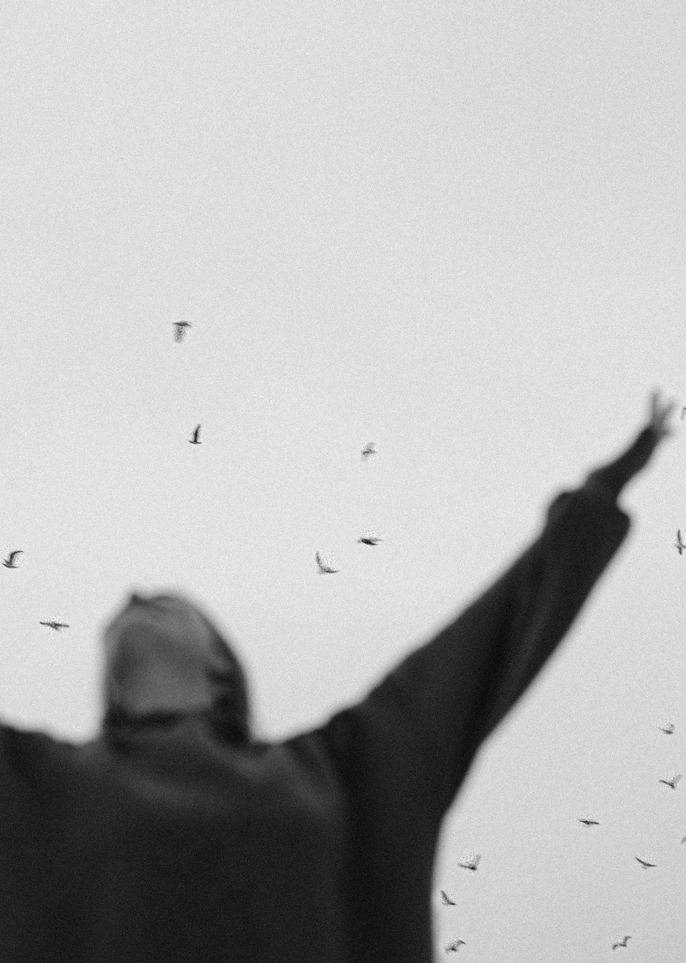 A black-and-white image shows a blurred figure with arms raised toward the sky, surrounded by birds in flight—symbolizing freedom, healing, and release. This visual metaphor powerfully aligns with the transformative potential of EMDR in Palm Beach County, FL, including EMDR therapy in Boca Raton, FL and support from EMDR group therapy in Palm Beach County, FL for trauma recovery and emotional liberation.