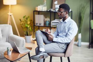 A person takes notes while looking at their laptop. Learn more about the support psychoeducational testing in Tampa, FL can offer. Search “psychoeducational testing near me” to learn more today. 