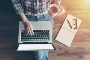 A person types on their laptop with one hand while holding a cup in the other. This could represent the convenience of online EMDR in Florida. Contact an online EMDR therapist in Florida for online EMDR therapy in Florida today!