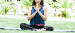A woman holds hands together while sitting on a yoga mat outside. THis could represent the resources in St. Pete for addressing anxiety. Learn more about anxiety therapy in Tampa, FL by contacting a therapist St. Petersburg, FL or searching for "therapist in st. pete" today.