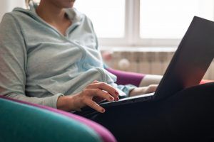 A person sits in a comfy chair as they type on their laptop. This could represent meeting with an online therapist in Florida form the comfort of home. Learn more about online couples counseling in Florida and more by contacting an online couples counselor in Tampa Bay, FL today. 33703