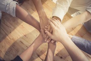 A close up of people stacking their hands on one another while sitting in a circle. This could symbolize the support group therapy for men in St Petersburg, FL can offer. Learn more about the help that men's group therapy in Tampa, FL can offer by contacting a therapist in St. Pete, FL today.