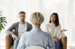 An image of a couple sitting in seprate chairs across from an attentive therapist. This could represent meeting with a marriage counselor in Tampa, FL to work out relationship issues. Contact a marriage counselor to learn more about our services including discernemnt counseling in Tampa, FL and more! 33609 | 33704 | 33703 