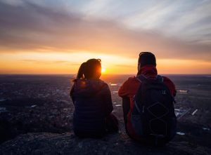 A couple sit together on a hill as the sun sets over the horizon. This could represent overcoming relationship issues with online couples counseling in Florida. Learn more about online marriage counseling in Florida and other services by contacting an online couples counselor in Tampa Bay, FL for support. 33609