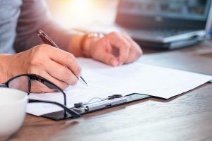 A close up of a person filling out a form on a clipboard. This could represent someone in the process of psychological testing in Tampa, FL. Learn more about psychoeducational testing near me and the benefits of a psychoeducational evaluation today. 