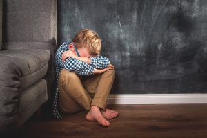 A child covers their face while sitting on the ground next ot a chair. A PCIT therapist in Tampa, FL can help you connect with your child via PCIT therapy in St. Petersburg, FL and more. Or, search PCIT therapy near me today.