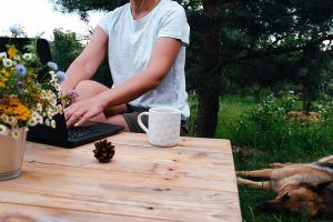 A person sits at an outdoor table while typing on a laptop. Learn more about how an online therapist in Florida can offer support by searching for online marriage counseling in Florida and other services. 