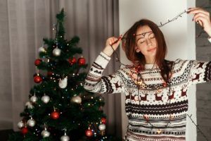 Brunette woman in white reindeer sweater holdi