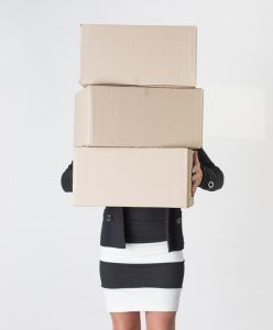 Young adult female carry a stack of boxes during a move from one office to another