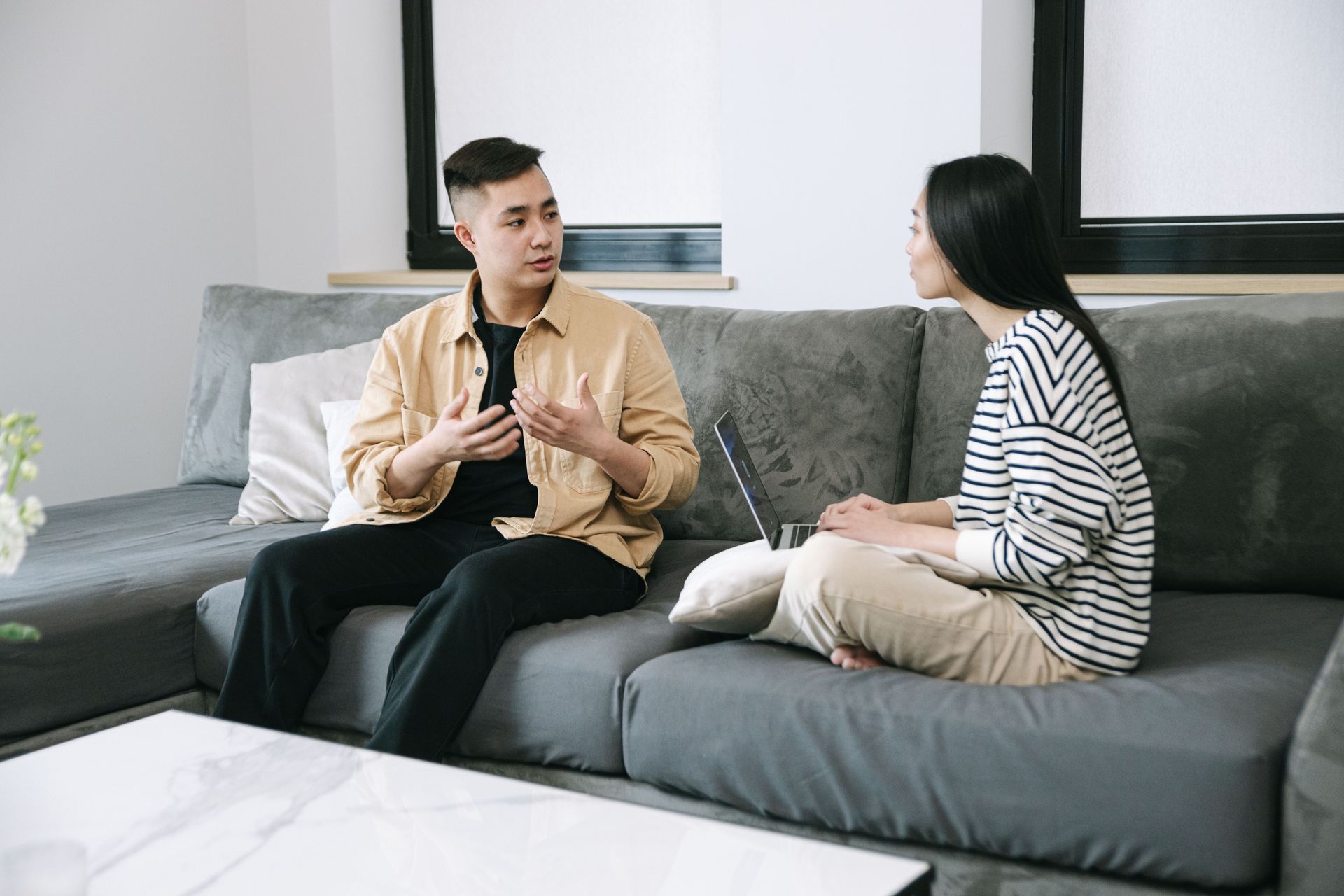 Two adults sitting together on a couch, talking calmly after a disagreement 