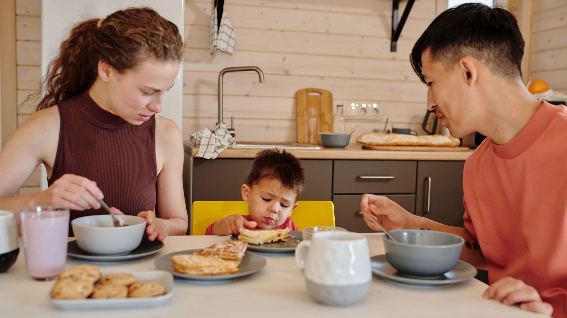 family with kids sitting at a kitchen table at breakfast