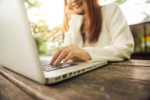 Woman sitting at a table on her laptop. Do you find it hard to have time to go to therapy? Discover how online therapy in Atlanta, GA can help you manage your time.