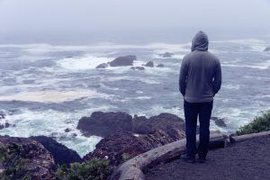 A teen stands near a rocky shore alone. A therapist for teens in Atlanta, GA can offer support from the comfort of home. Learn more about online therapy for teens in Atlanta, GA and other services by contacting an online therapist for teens.