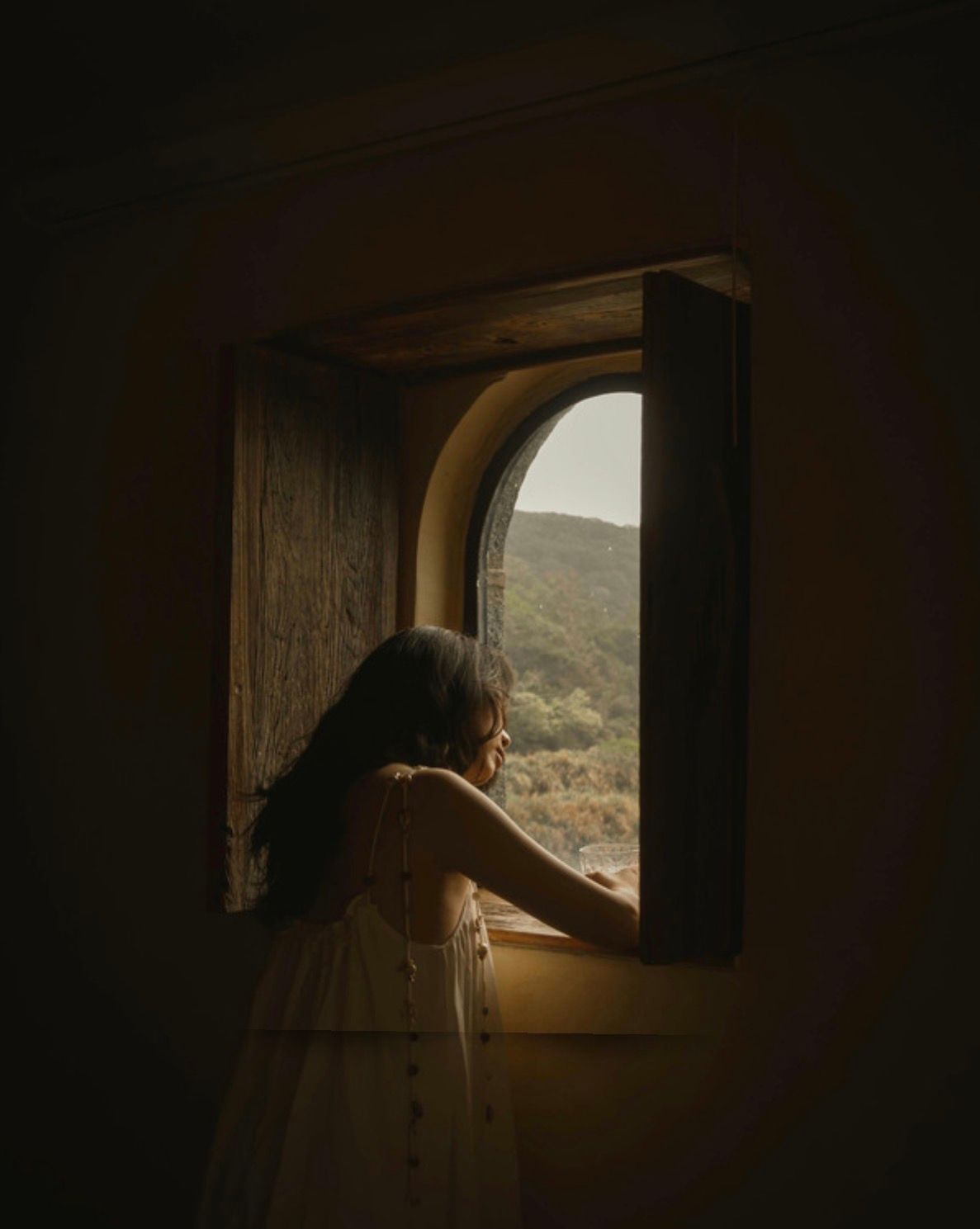 Woman looking outside of a window contemplating.